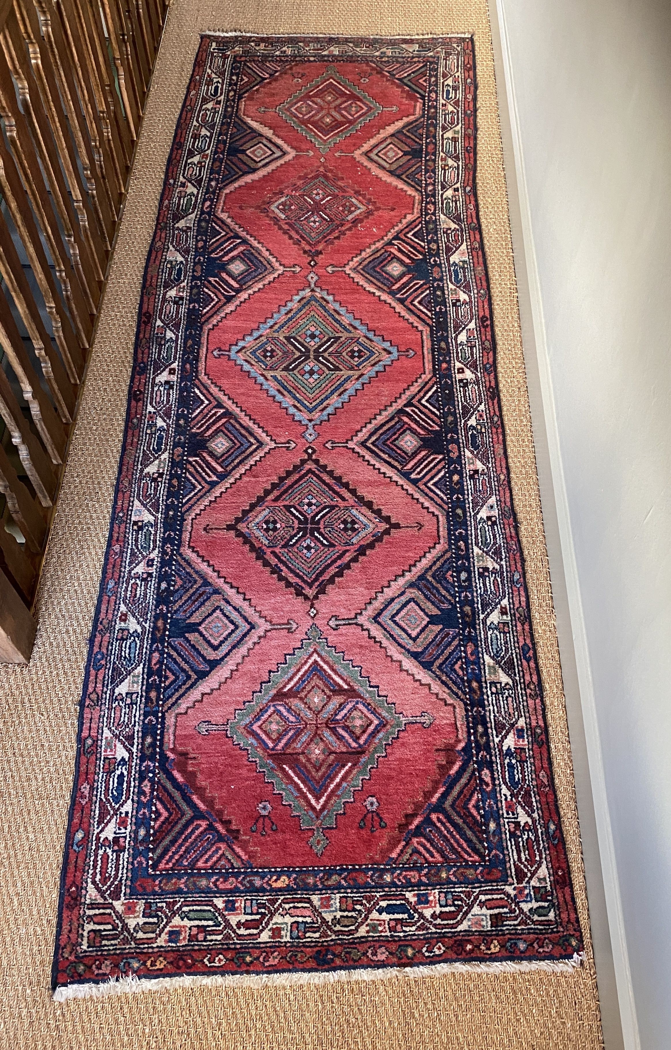 A Persian red ground runner, with five central lozenges, multi-bordered, 303 x 98cm